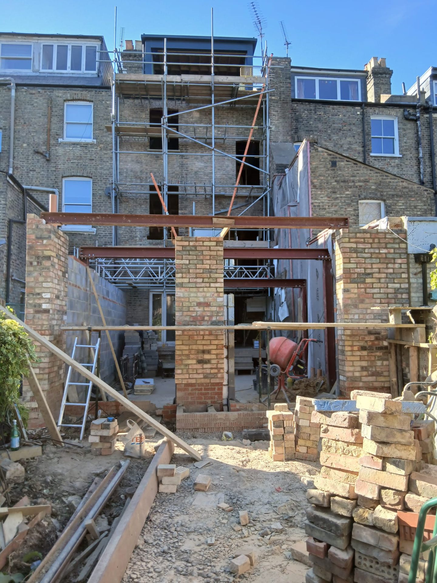 A live structural site audit on a London townhouse renovation - exposed steel frame, brick piers and scaffolding.